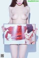 A naked woman holding up a book with a picture of a lobster.