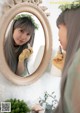 A woman is looking at her reflection in a mirror.